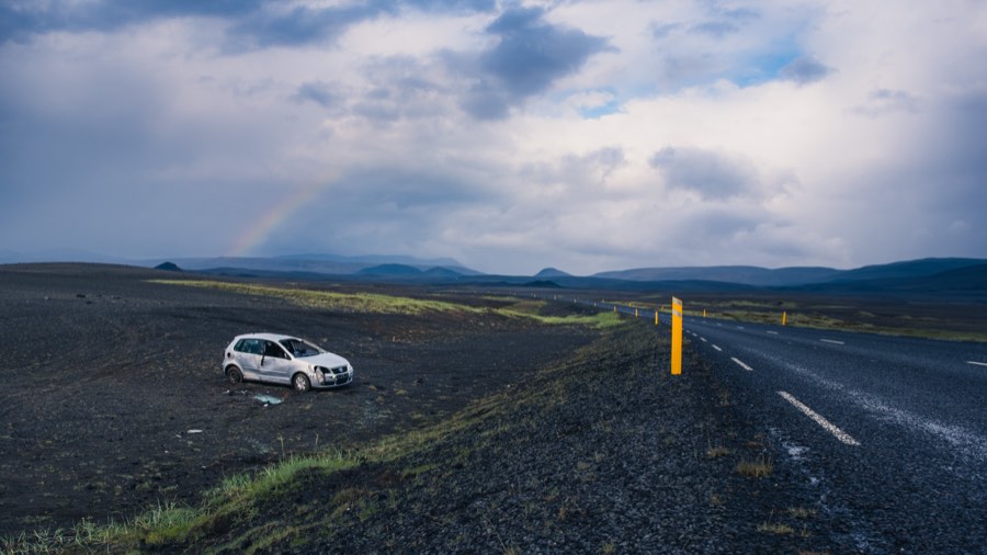 Abandoned car beside the ring road in a black lava field
